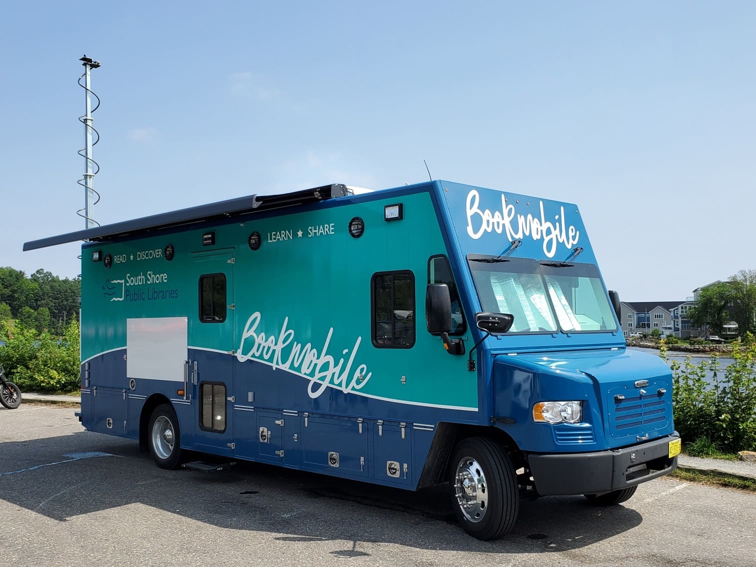 The South Shore Public Libraries Bookmobile — a teal-and-navy van lettered 'Bookmobile' on the side — parked next to a harbour.